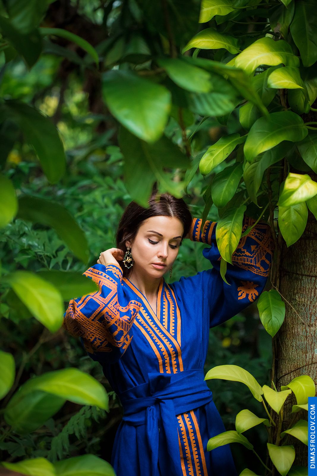 Portrait of a stylish woman in ethnic blue dress among jungle leaves