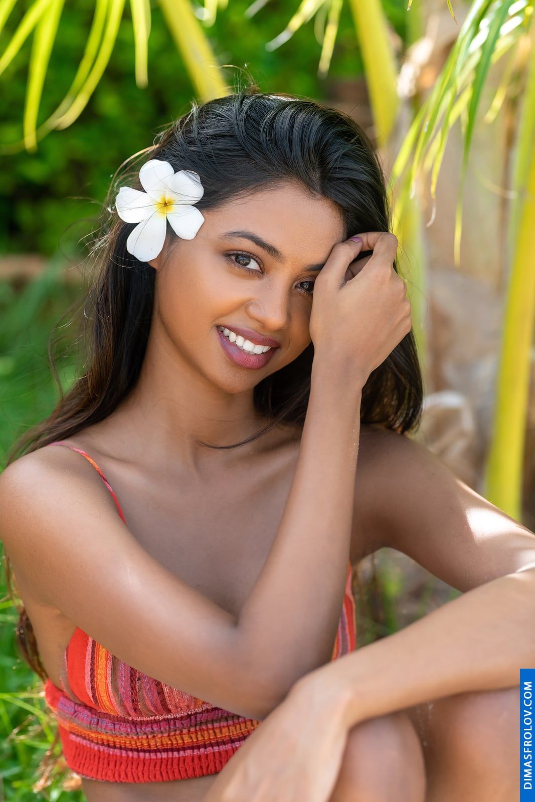 Smiling beauty with a tropical flower in her hair during a portrait session