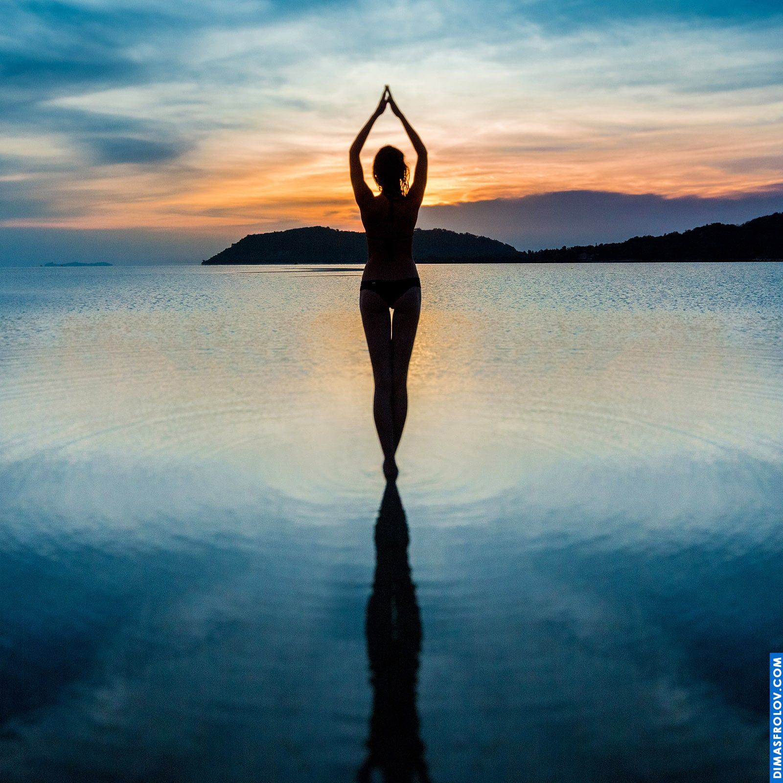 Silhouette of a woman standing in the water during sunset meditation