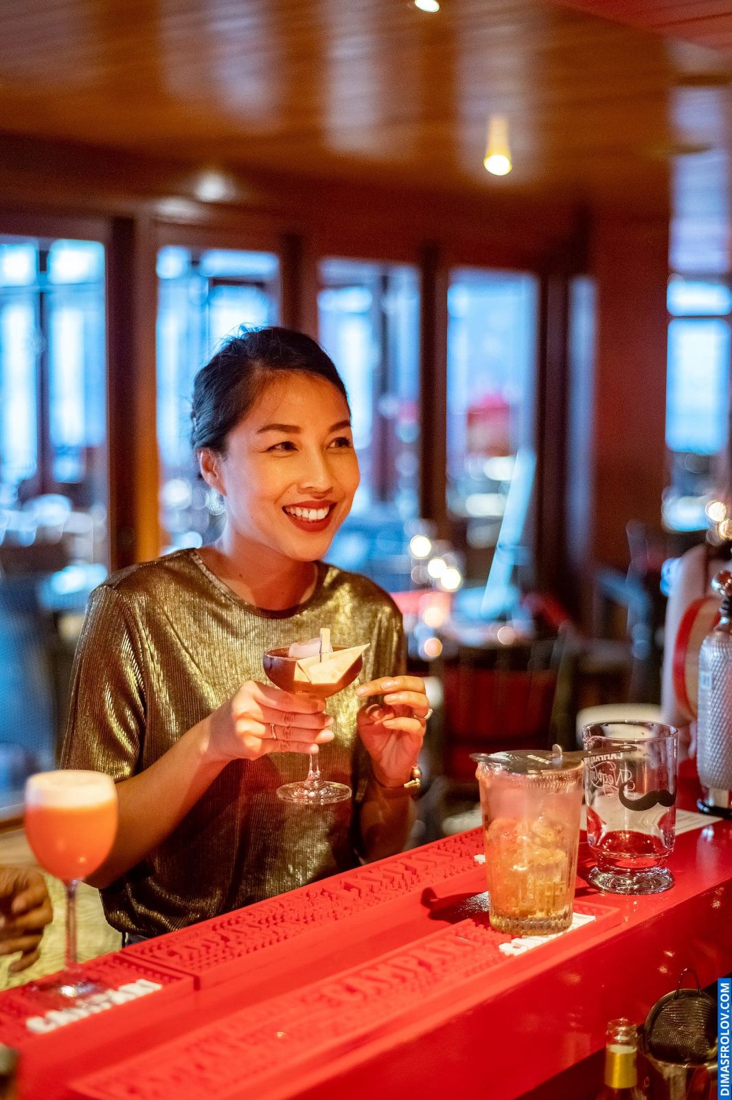 Smiling woman enjoying a cocktail at vibrant event bar