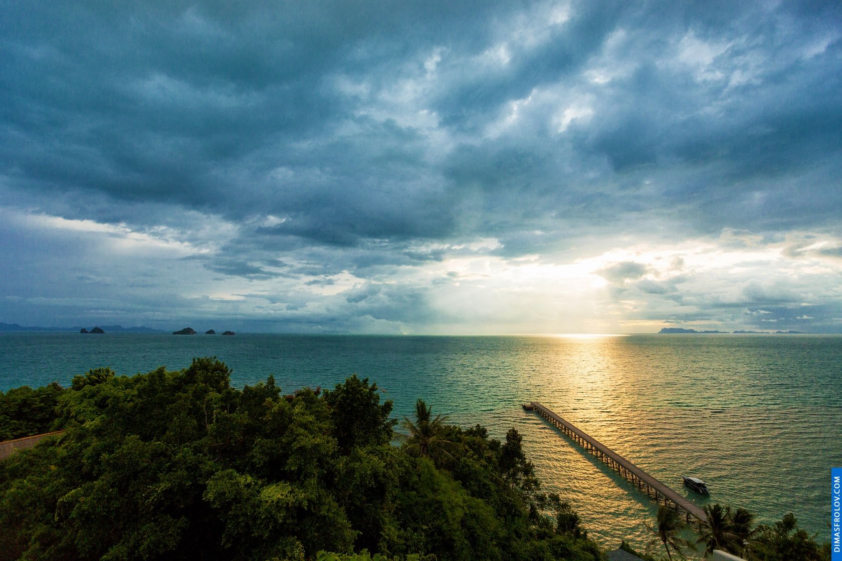 Dramatic coastal scene with dark, moody clouds over the ocean and a hint of sunlight breaking through