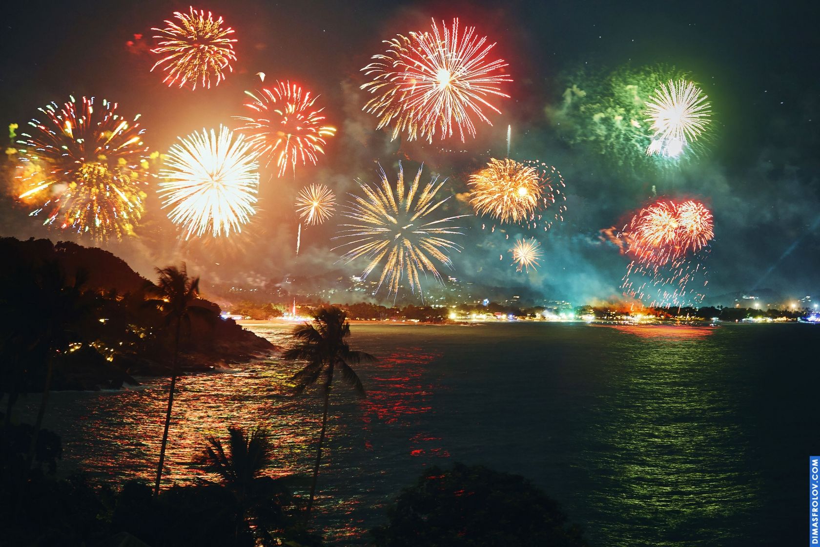 Spectacular fireworks display over a dark cityscape at night, illuminating the sky with vibrant colors